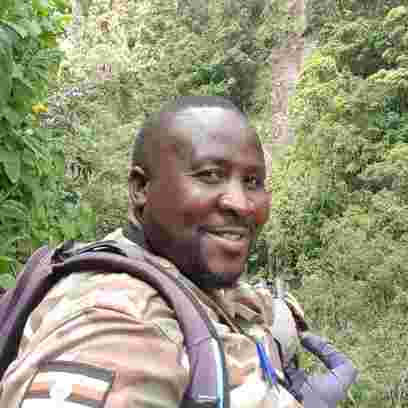 Man looking at the camera and smiling with lush greenery in the background. 