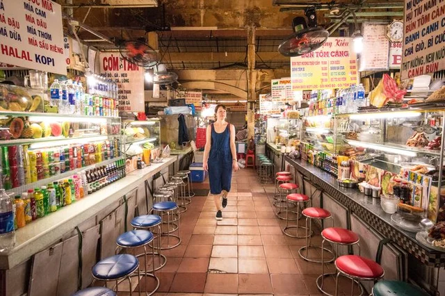A solo female traveller walking through food stalls in the market in Ho Chi Minh City, Vietnam.
