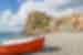 A boat pulled onto the beach of Tropea with Castello Ruffo beyond on a rock outcropping