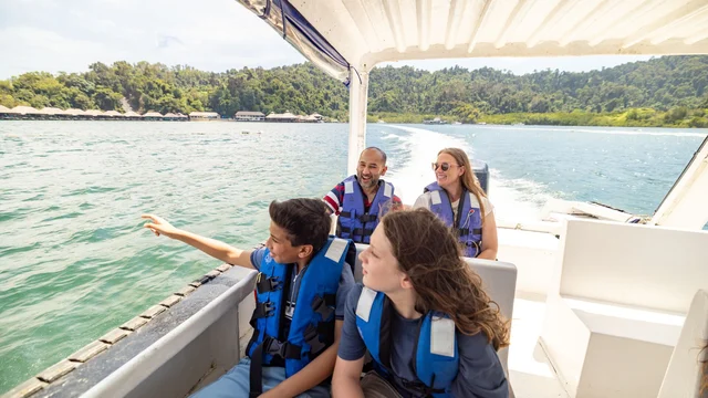 Two children wearing life jackets sit in front of two adults in a boat