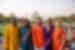 Group of varied ages pose with smiles in colourful elegant clothing standing at a distance in front of the Taj Mahal