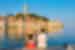 Two travellers sit with their feet in the Adriatic looking out at the waterfront town of Rovinj, Croatia